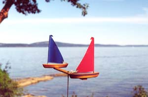 WindRacer Garden Art with Red and Blue Sails on the edge of a lake